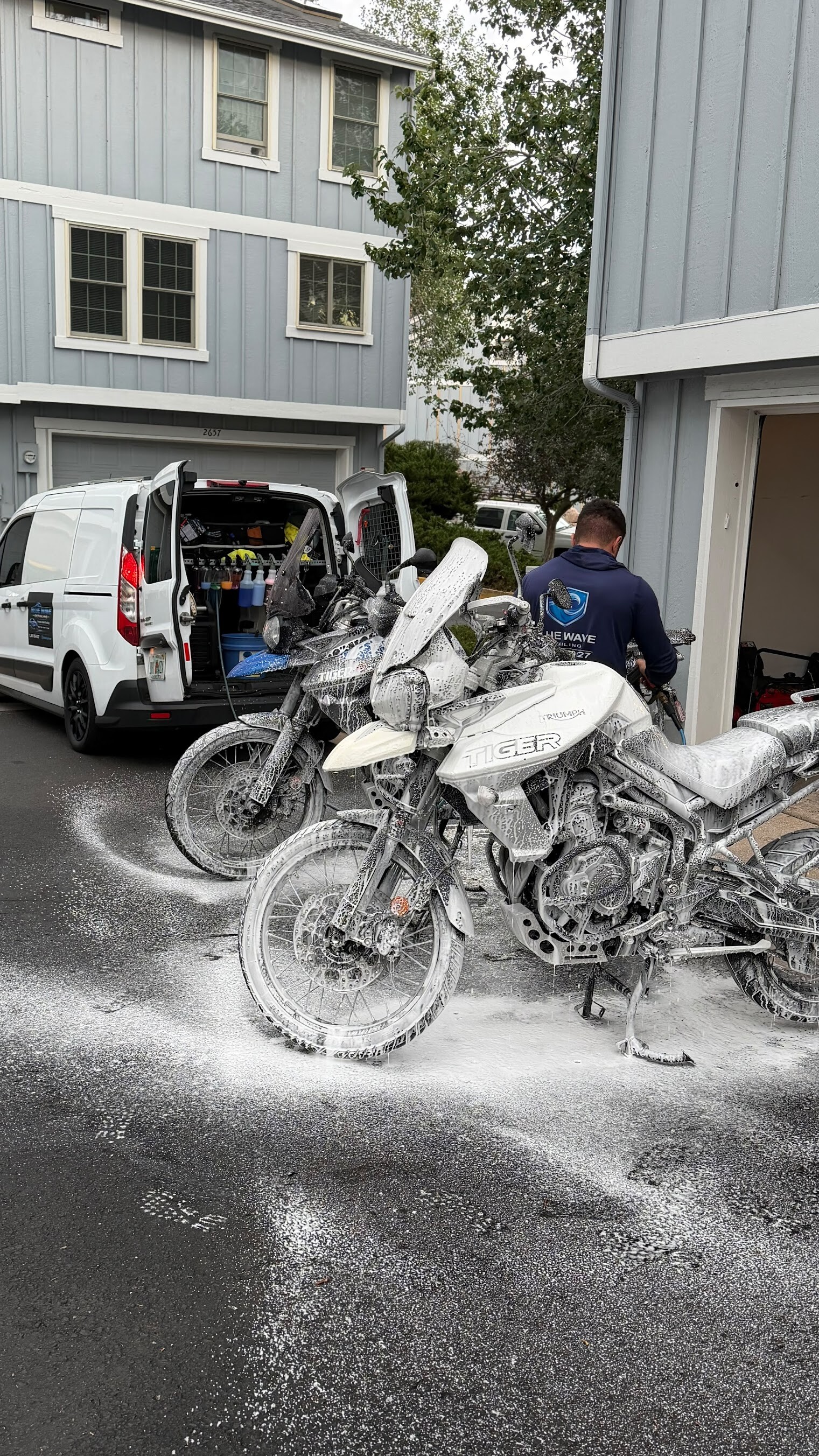 Two Triumph Tiger motorcycles being washed next to the service van
