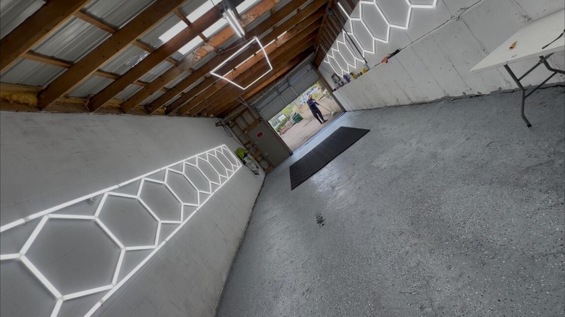 Inside the Blue Wave Detailing shop, with hexagon lighting and an open bay door